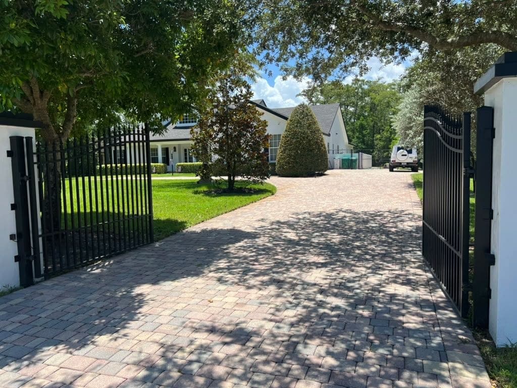 Aluminum swing gate and matching fence line along a paver driveway