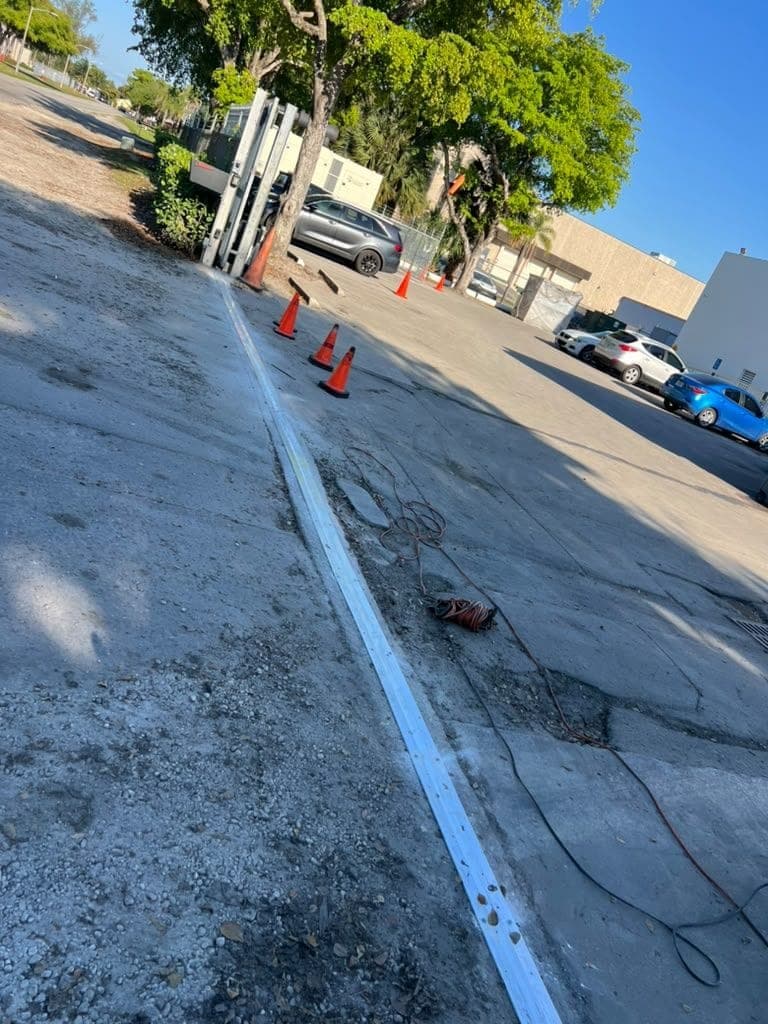 Technician replacing the ground track under a sliding driveway gate